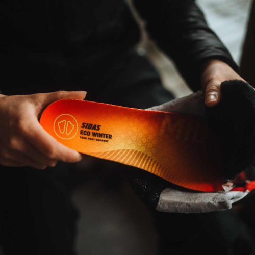 Person holding an orange shoe insole with Sidas branding.